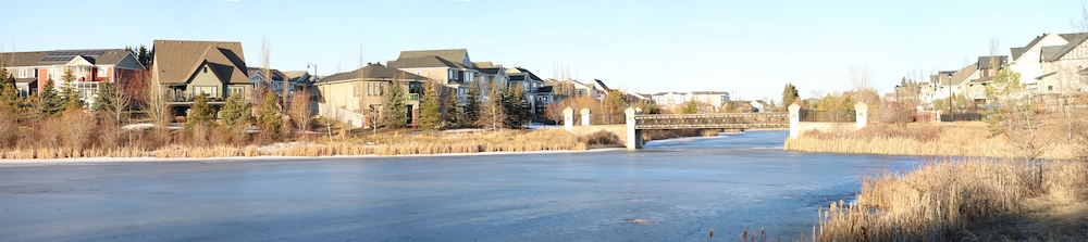 A panoramic view of a bridge over a lake in Griesbach Edmonton.